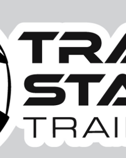A black and white graphic logo featuring a stylized racing helmet on the left and the words 'TRACK START TRAINING' in bold black lettering on a white sticker-like shape, set against a light gray background.