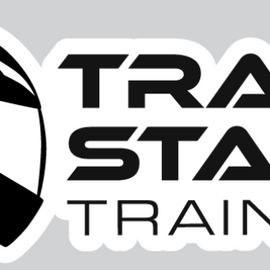 A black and white graphic logo featuring a stylized racing helmet on the left and the words 'TRACK START TRAINING' in bold black lettering on a white sticker-like shape, set against a light gray background.