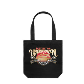 Black tote bag with design of the words destination unknown in front of a sunset, with motorbike handlebars on black tall tote bag