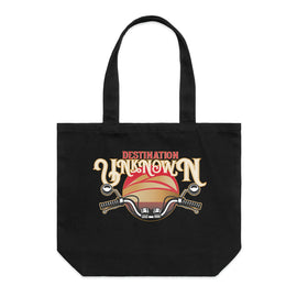 Black tote bag with design of the words destination unknown in front of a sunset, with motorbike handlebars on black wide tote bag