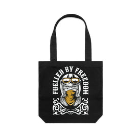 A black canvas tote bag with a graphic print of a helmeted motorcycle rider wearing a bandana, with the text 'FUELLED BY FREEDOM' in white.