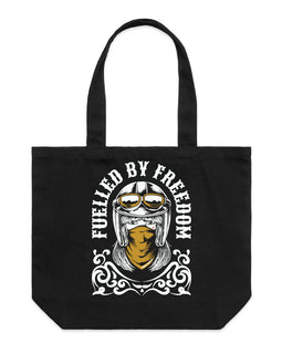 A black canvas tote bag with two top handles, featuring a graphic print of a helmeted motorcycle rider with goggles and the text 'FUELLED BY FREEDOM' in white.