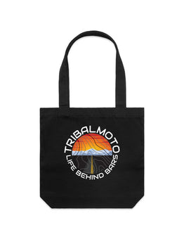 circle design includes the words TribalMoto and Life Behind Bars with a sunset, mountains and a road. Layered with topographical lines on black tote