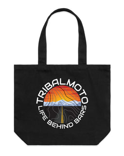 circle design includes the words TribalMoto and Life Behind Bars with a sunset, mountains and a road. Layered with topographical lines on black tote wide