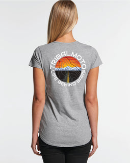 Design of a sunset with road and mountains, layered with topography lines and surrounded by the words TribalMoto Life behind bars on a grey tee