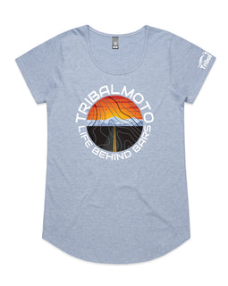 Design of a sunset with road and mountains, layered with topography lines and surrounded by the words TribalMoto Life behind bars on ablue tee