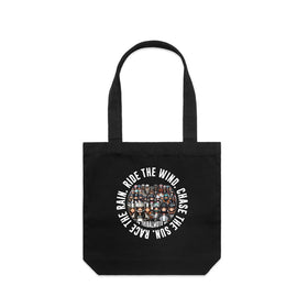 Black tote bag with a design of motorcycle lady riders and the words Ride the wind, Chase the sun, Race the rain in a circle around the outside.