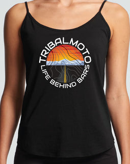 circle design includes the words TribalMoto and Life Behind Bars with a sunset, mountains and a road. Layered with topographical lines on black tank